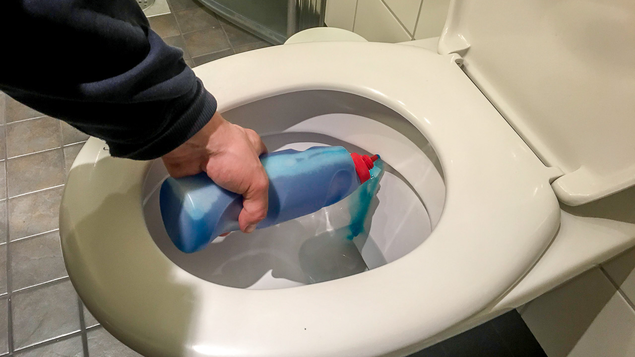 Filled blow moulded bottle being used to clean toilet.